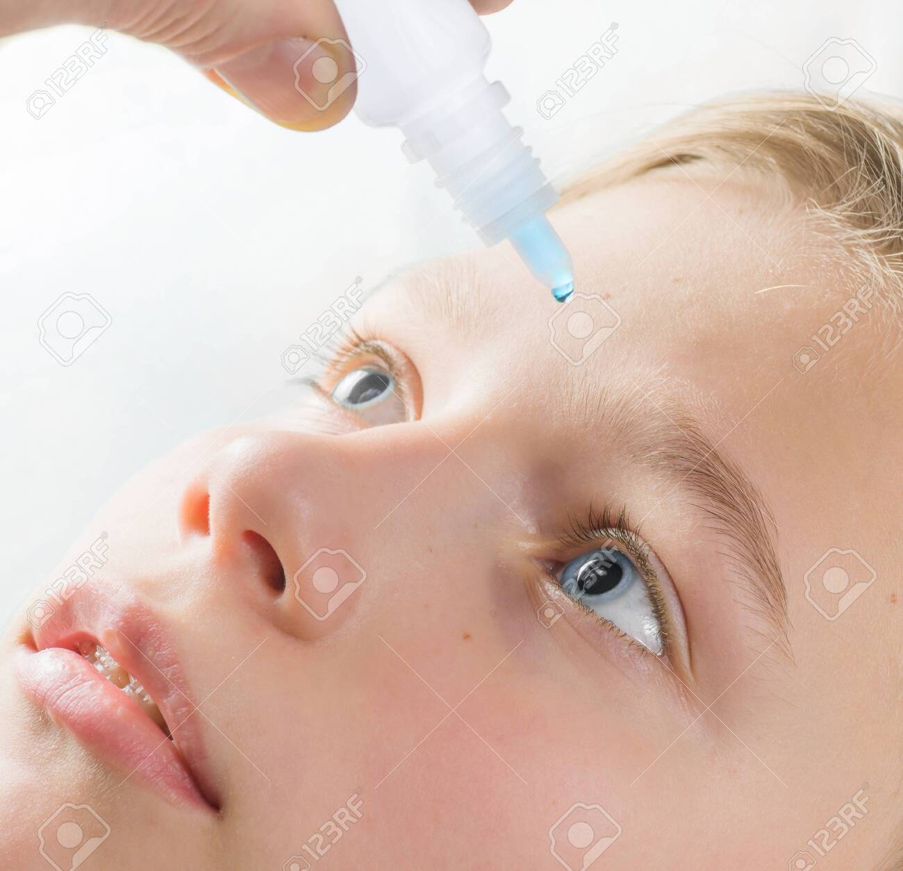 Closeup view of teen boy applying eye drop on white background. - 138065983 Closeup view of teen boy applying eye drop on white background. - 138065983