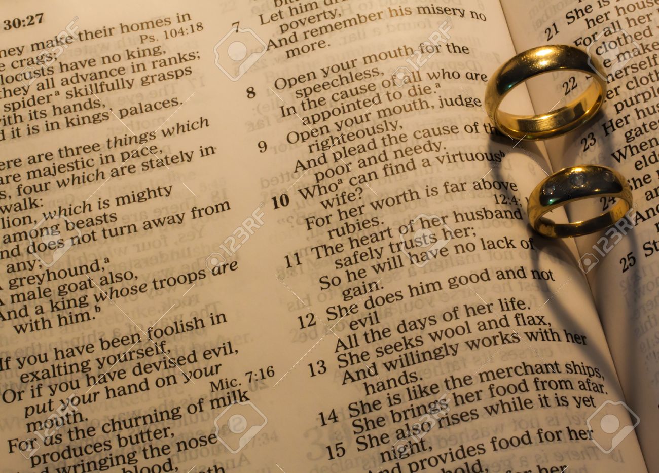 wedding rings making heart shaped shadows on bible pages stock photo