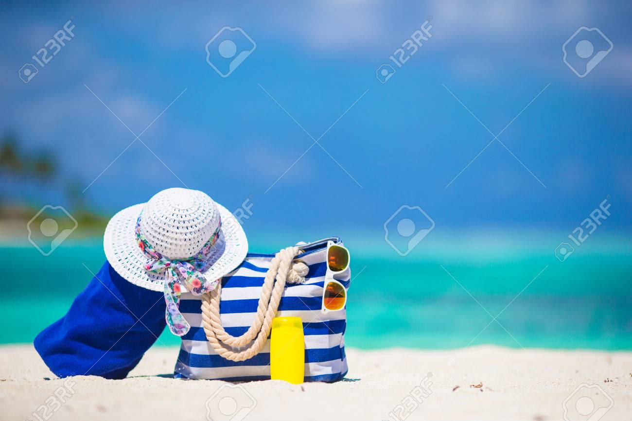 Blue stripe bag and towel, straw white hat, sunglasses, sunscreen bottle on exotic beach - 38983824 Blue stripe bag and towel, straw white hat, sunglasses, sunscreen bottle on exotic beach - 38983824