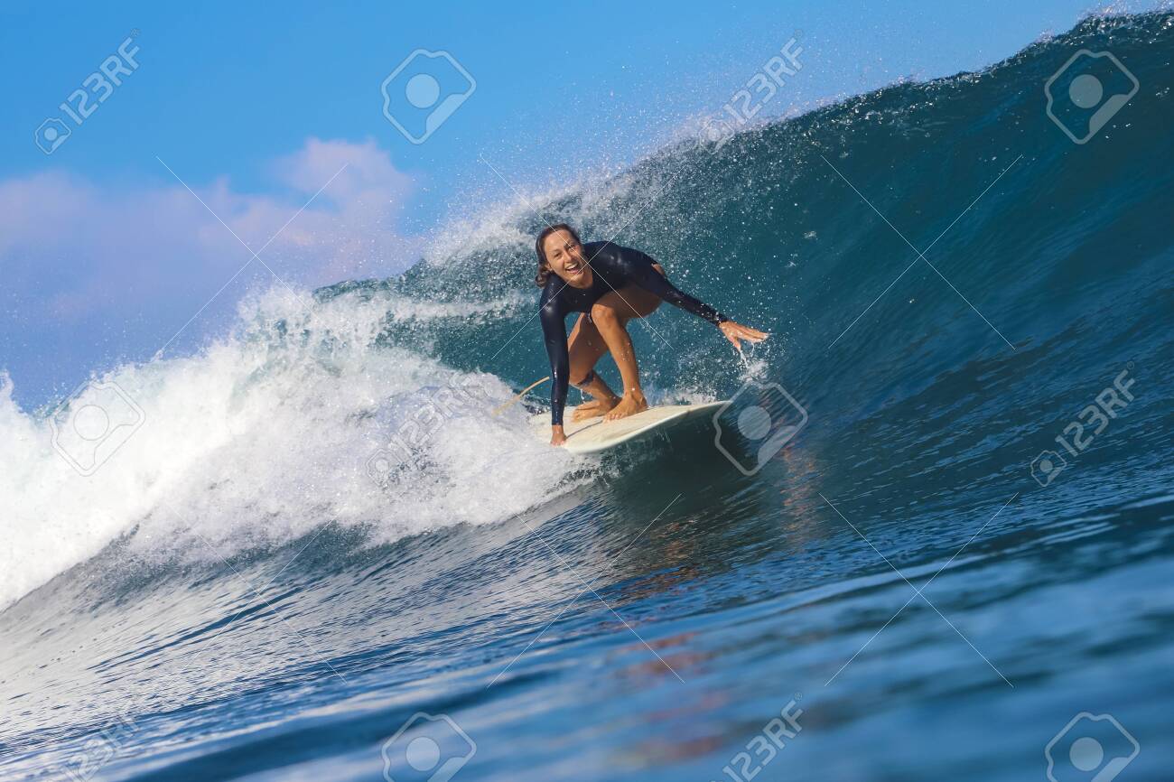 Female surfer on a blue wave at sunny day - 142664846 Female surfer on a blue wave at sunny day - 142664846