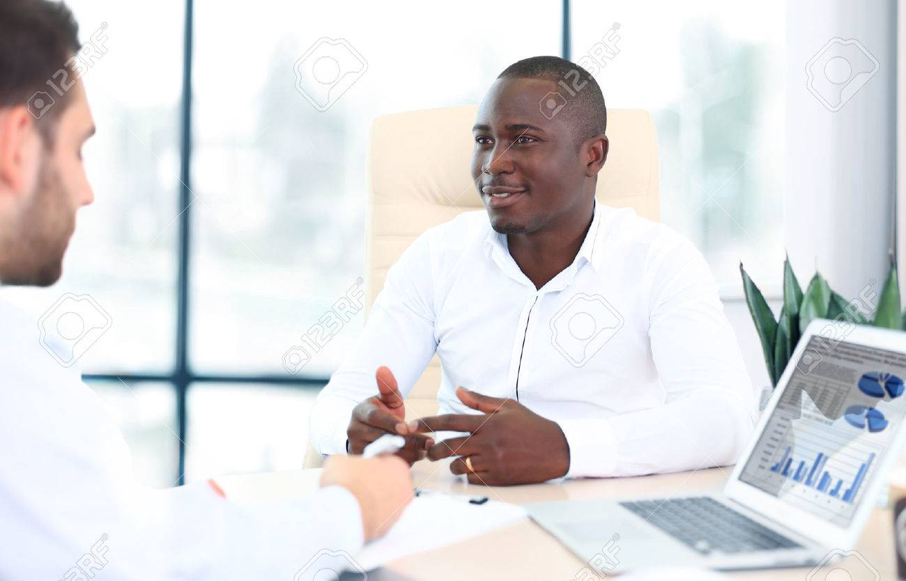 Image of two young businessmen interacting at meeting in office - 48969015 Image of two young businessmen interacting at meeting in office - 48969015