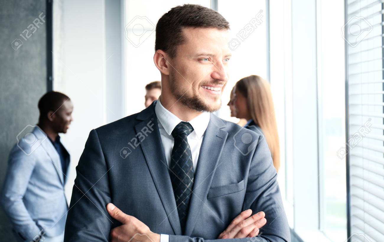 Businessman with colleagues in the background in office - 69561085 Businessman with colleagues in the background in office - 69561085