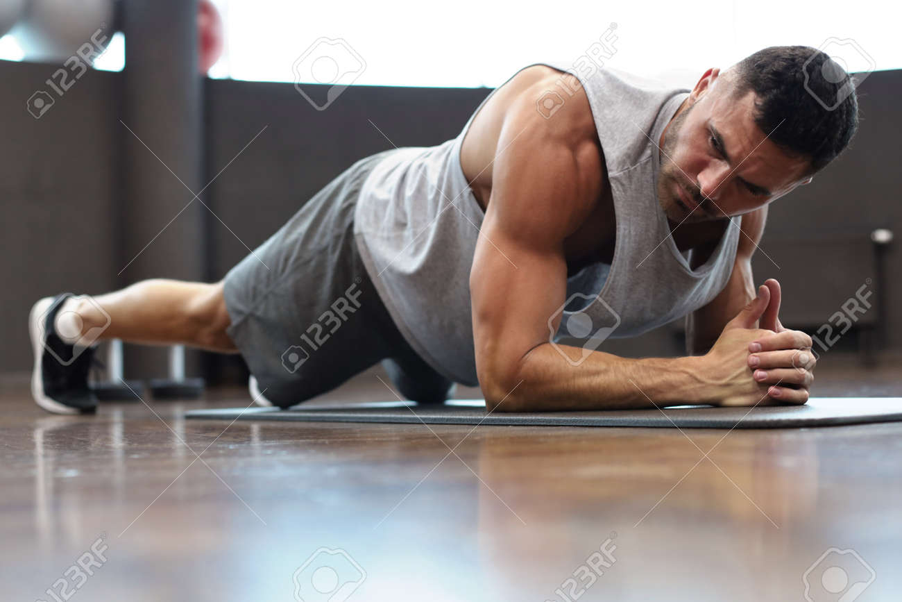 Portrait of a fitness man doing planking exercise in gym - 126908621 Portrait of a fitness man doing planking exercise in gym - 126908621
