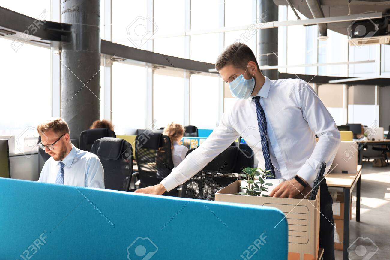 Dismissal employee in an epidemic coronavirus covid-19. Sad dismissed worker are taking his office supplies with him from office - 143334478 Dismissal employee in an epidemic coronavirus covid-19. Sad dismissed worker are taking his office supplies with him from office - 143334478