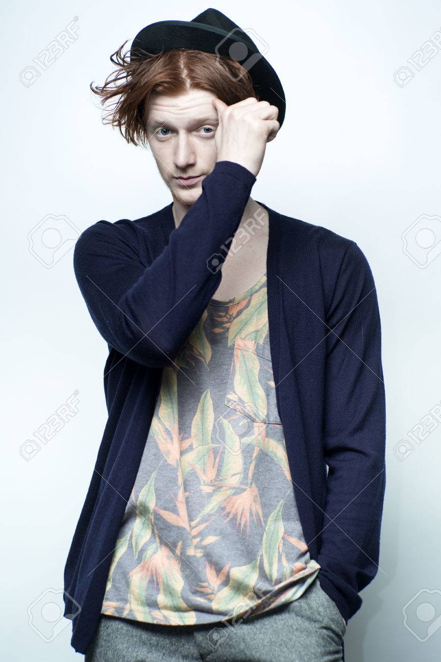 かわいい赤髪若いおしゃれなひげを剃っていないスタイリッシュな男性一カラフルな花柄プリントの黒い帽子と白い背景 画像の垂直方向のスタジオに立って青ジャージと下着で の写真素材 画像素材 Image