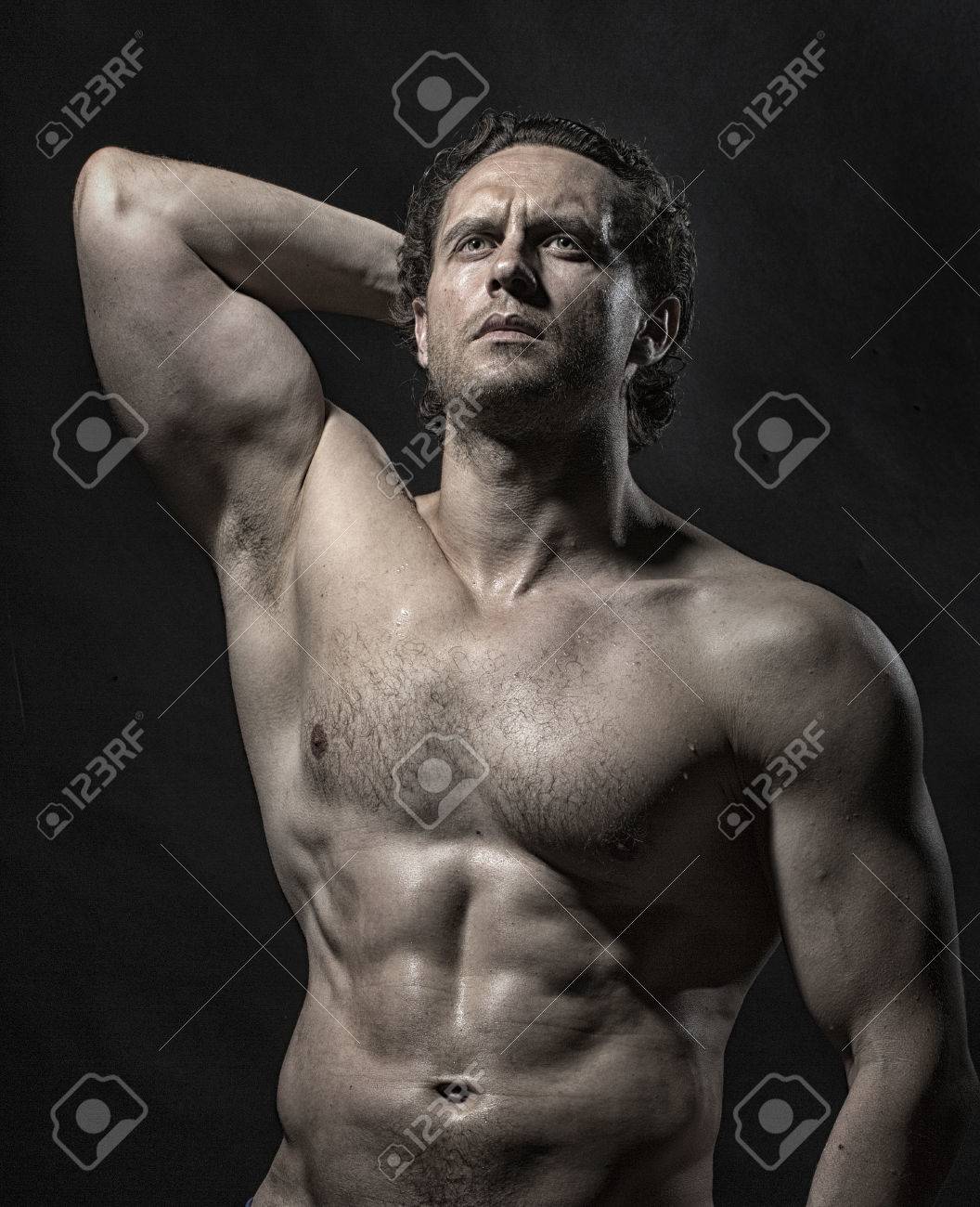 Stattliche Stark Mürrische Nackten Muskulösen Unrasiert Männliche  Bodybuilder Mit Schönen Geraden Athletischen Körper Mit Erhobener Hand Und  Nackte Brust, Die Auf Studio Schwarzen Hintergrund Entfernt, Vertikale Foto  Lizenzfreie Fotos, Bilder und Stock