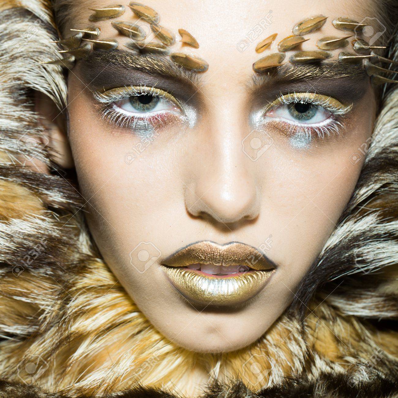 Banque d\u0027images , Portrait Gros plan d\u0027une belle jeune femme sauvage avec lumineux animaux singe doré maquillage avec des épines sur le visage en manteau de
