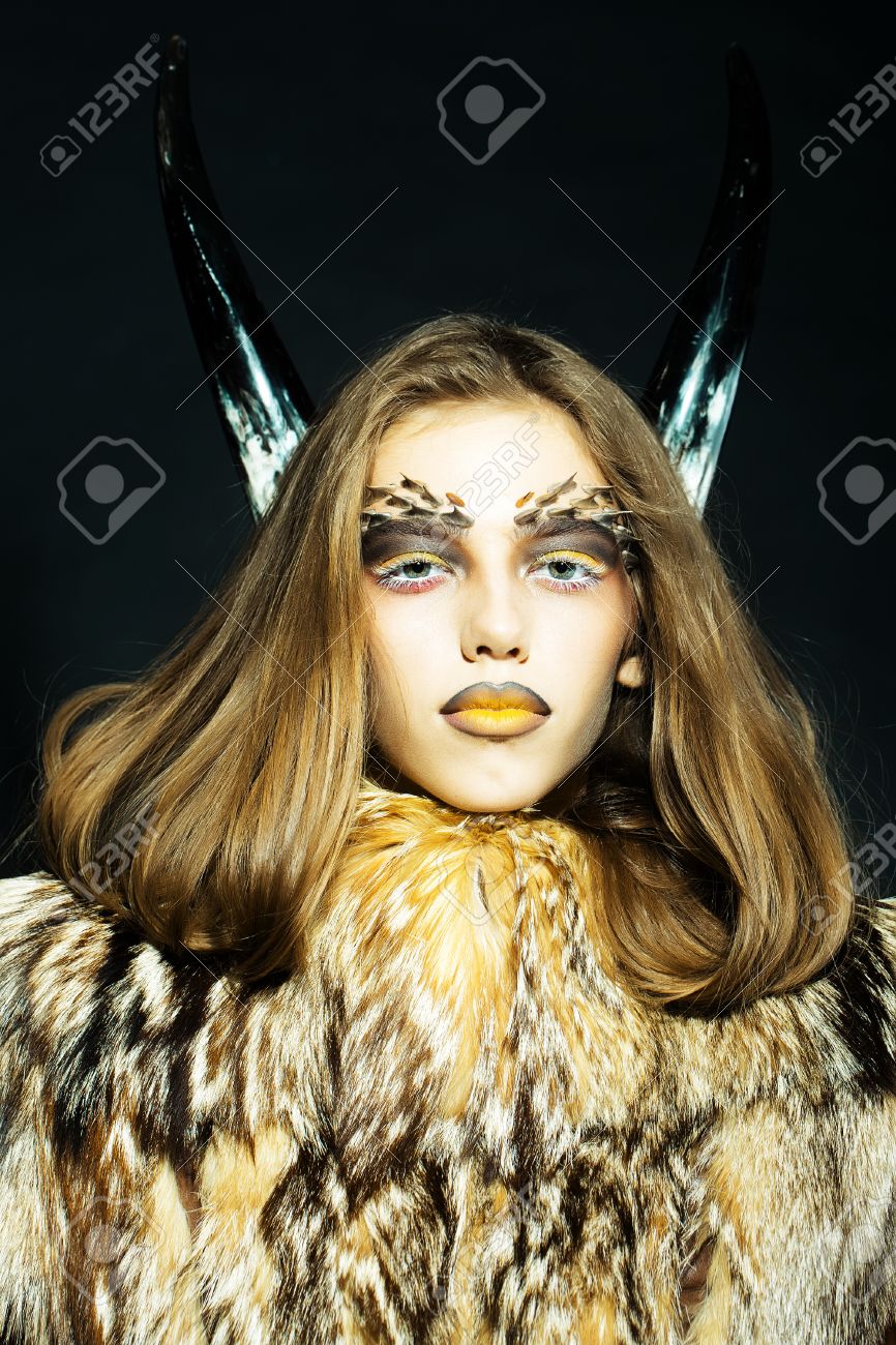 明るい黄金の動物猿メイク顔と黒の背景画像の垂直方向に毛皮のコートの角にトゲがあると 1 つの美しい野生若い女性のポートレート クローズ アップ の写真素材 画像素材 Image