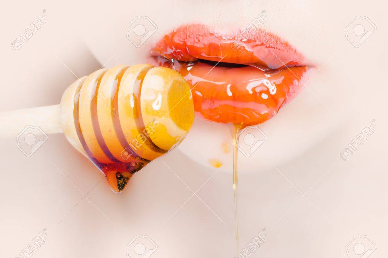 Sensual female red lips eating honey from wooden spoon closeup - 56087184 Sensual female red lips eating honey from wooden spoon closeup - 56087184