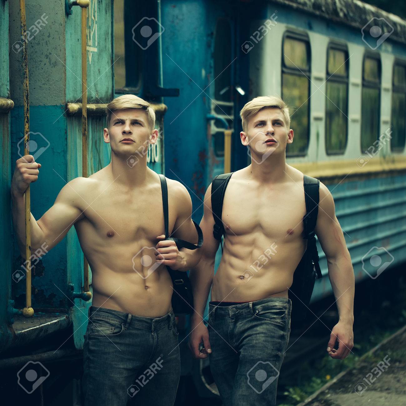 Meninos Bonitos Com Corpo Musculoso Em Pé Sem Camisa Em Calças Com Belo  Tronco Perto De Azul Velho Trem Ferroviário Foto Royalty Free, Gravuras,  Imagens e Banco de fotografias. Image 57112338