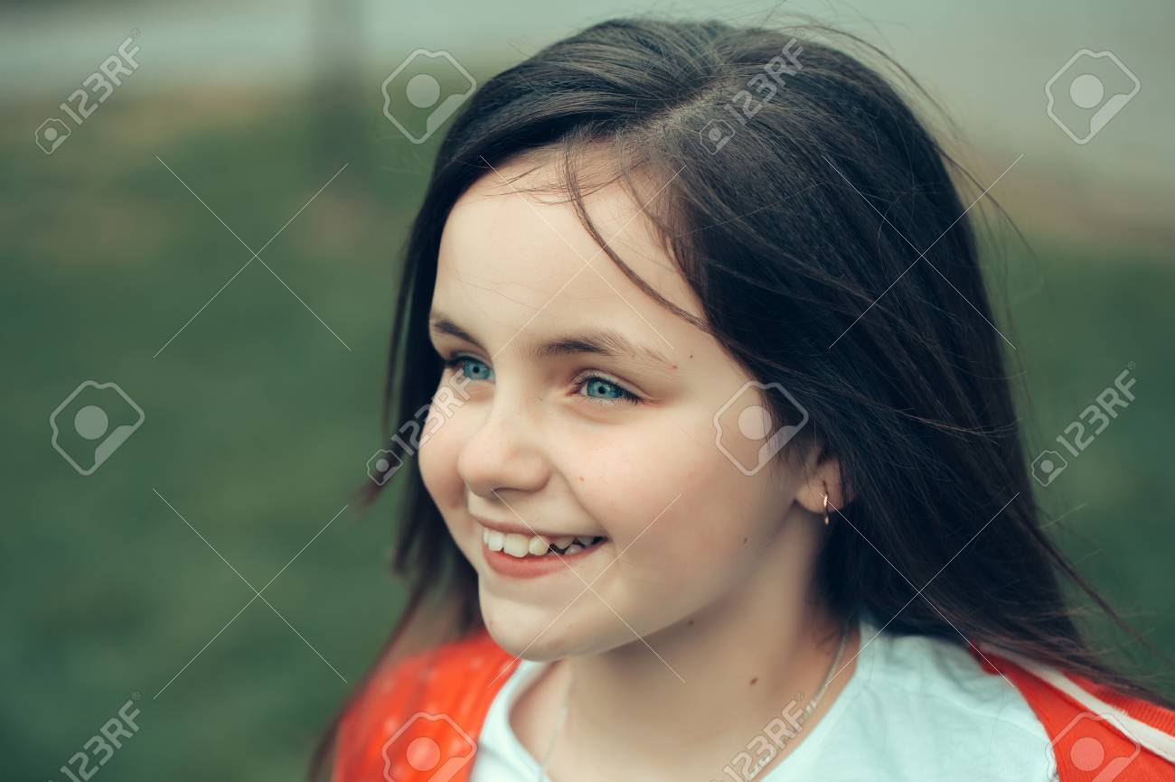 Visage Souriant Peu Jolie Fille Heureuse Enfant Aux Yeux Bleus Et Cheveux Bruns Gros Plan Exterieur Sur Fond Vert Floue Banque D Images Et Photos Libres De Droits Image