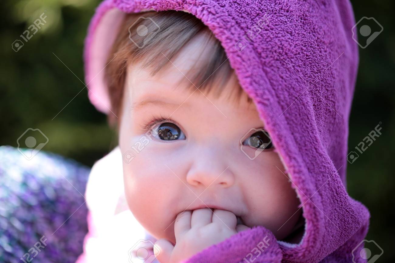 small cute baby girl with pretty face and funny eyes in hood stock