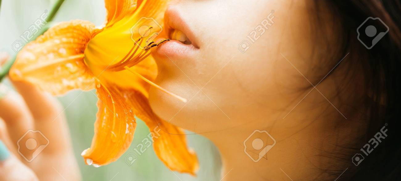 きれいな女性の顔に官能的なバラ色の唇キス明るいオレンジ色のユリの花は 晴れた日に開花 の写真素材 画像素材 Image