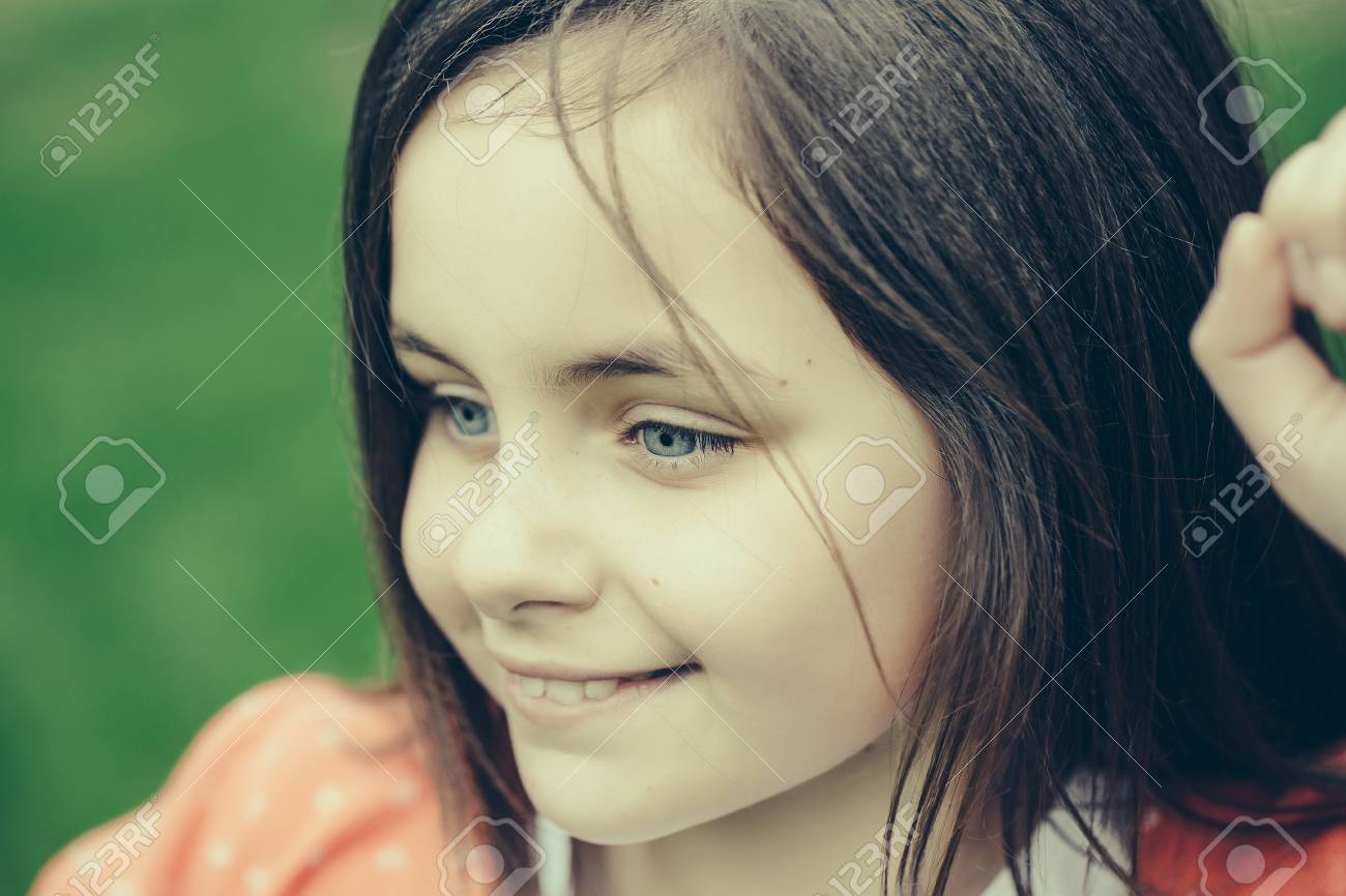 Souriant Visage De Petite Fille Mignonne Heureuse Fille Aux Yeux Bleus Et Closeup Exterieur De Cheveux Brune Sur Fond Vert Flou Banque D Images Et Photos Libres De Droits Image