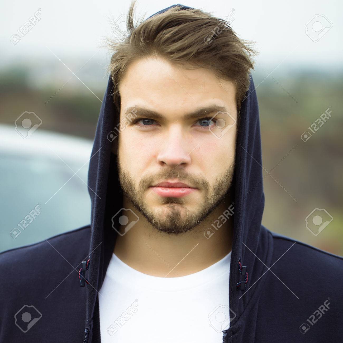 Jeune Homme Aux Cheveux Visage Brun Grave Et Les Yeux Bleus Barbus A Capuche Fonce Decontracte Sur La Tete Et Blanc T Shirt En Plein Air Banque D Images Et Photos Libres De Droits
