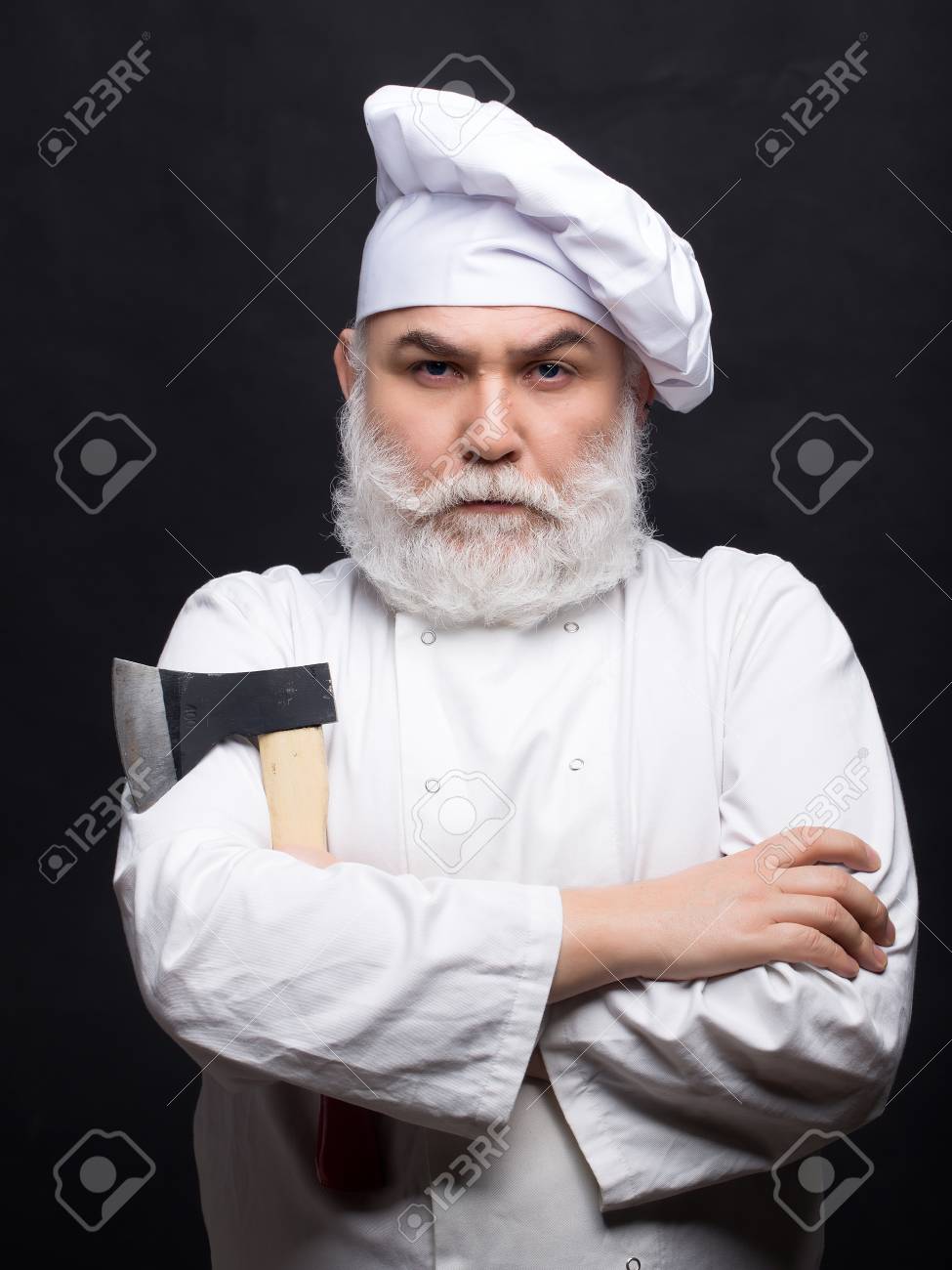 黒い背景にスタジオで鋭い斧とシェフ帽子で髭の男料理 の写真素材 画像素材 Image