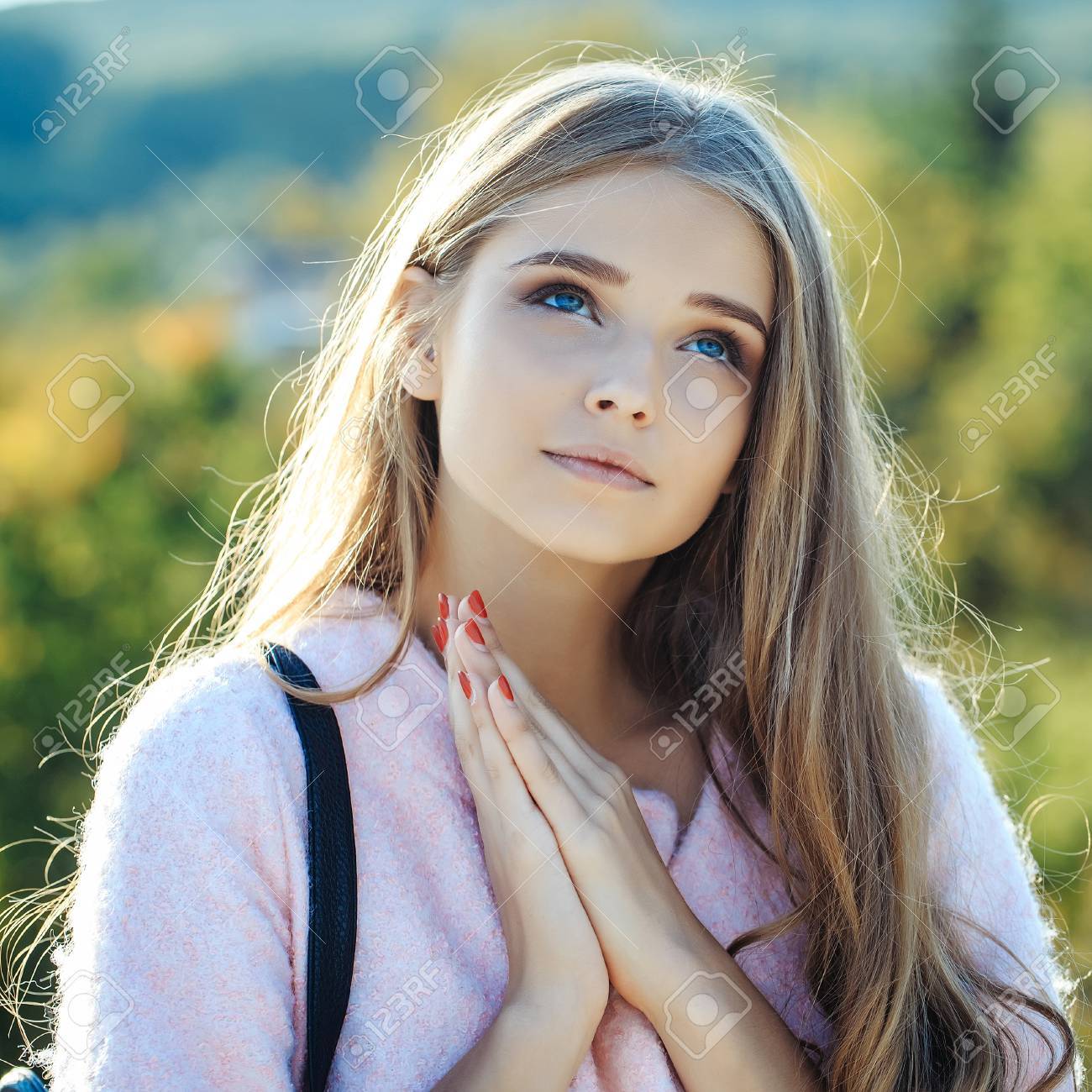 Pretty Girl Young Beautiful Woman Sexy Model With Blue Eyes And Long Curly  Blond Hair In Coat Prays Outdoors On Sunny Day On Natural Background Stock  Photo, Picture and Royalty Free Image., image size:1300x1300