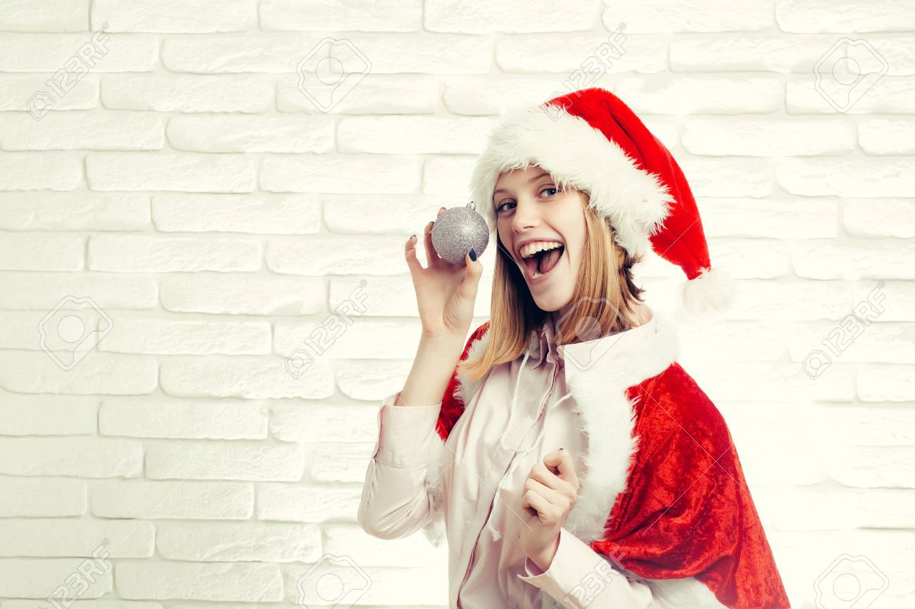 Junge Sexy Neues Jahr Frau Oder Cute Lachende Madchen Mit Hubschen Gluckliches Gesicht In Rot Weihnachten Weihnachtsmann Urlaub Hut Und Mantel Halt Silber Dekorative Kugel Auf Weissem Mauer Hintergrund Kopie Raum Lizenzfreie