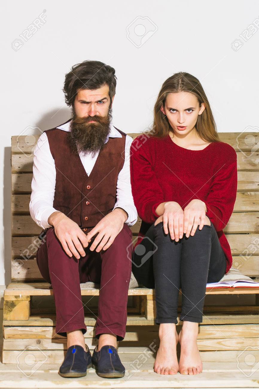 若いカップルは 一緒に時間を過ごします ハンサムな男 髭 ひげを生やしたヒップスターを眉をひそめているし かわいい美少女や美人に木製のパレット ソファーで膝の上の手で座る の写真素材 画像素材 Image