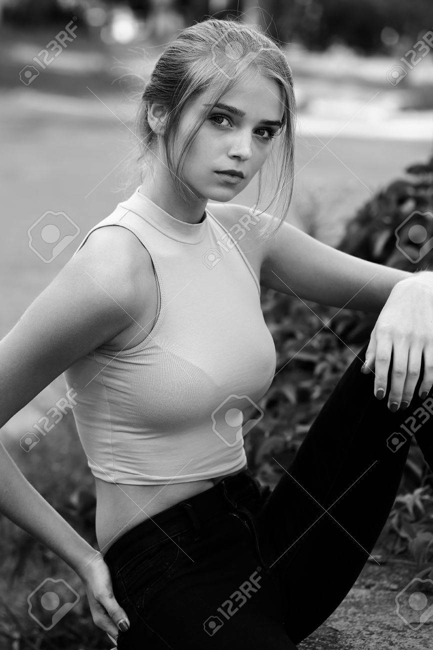 黒と白 背景をぼかした写真を屋外に座っているかわいい顔とシャツでお団子髪に結ばれると非常にセクシーな若い女性やファッションの女の子 の写真素材 画像素材 Image