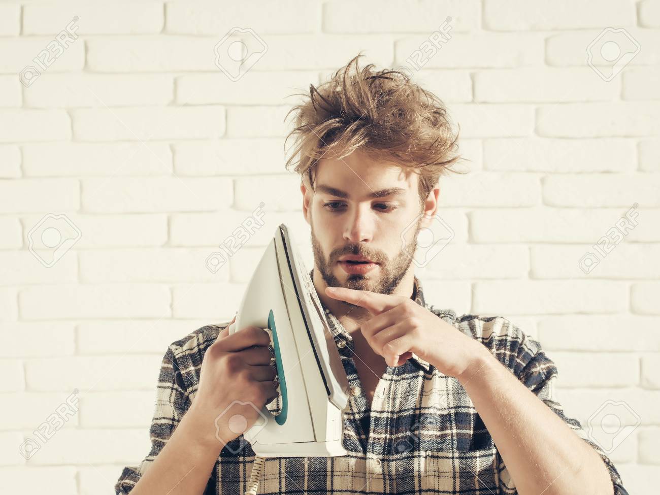 Young Handsome Man In Stylish Plaid Shirt Touches White Iron