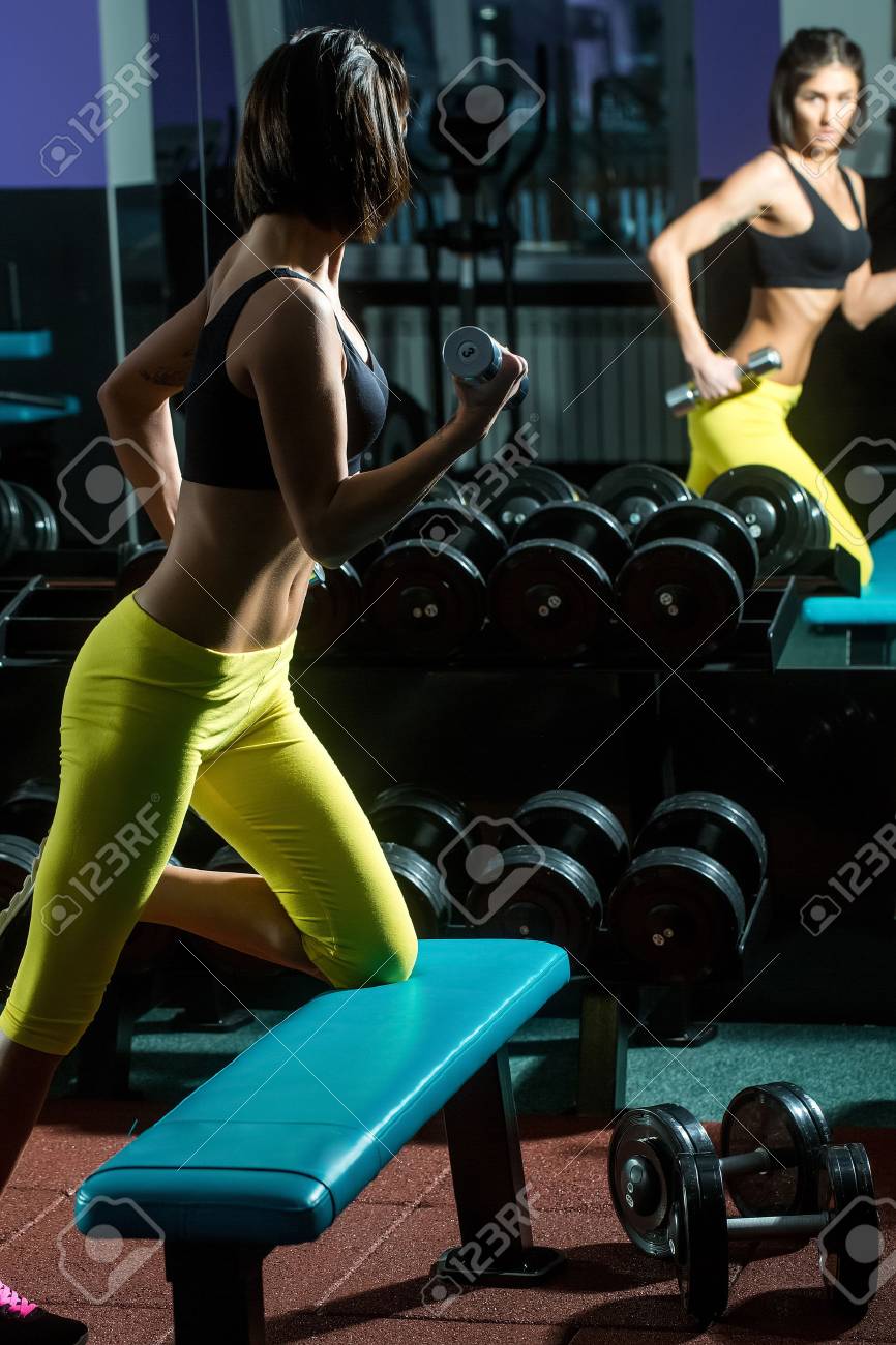 きれいな女性やトレーナーの近くの金属のダンベルとスポーツジムでトレーニング黄色パンツのセクシーな体とかわいい女の子 の写真素材 画像素材 Image