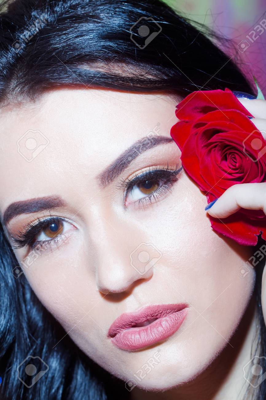 きれいな女の子やブルネットの髪と茶色の瞳と赤いバラ 自然な新鮮な花 紫色の背景に若い顔にスタイリッシュな化粧美人 の写真素材 画像素材 Image