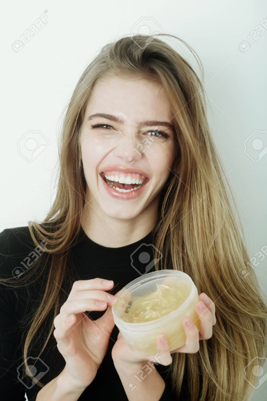 Glückliche hübsche Mädchen oder schöne Frau mit jungen Gesicht Haut und lange, blonden Haaren, ein Gel oder Balsam auf sexye Lippen aus Glas setzen Glückliche hübsche Mädchen oder schöne Frau mit jungen Gesicht Haut und lange, blonden Haaren, ein Gel oder Balsam auf sexye Lippen aus Glas setzen