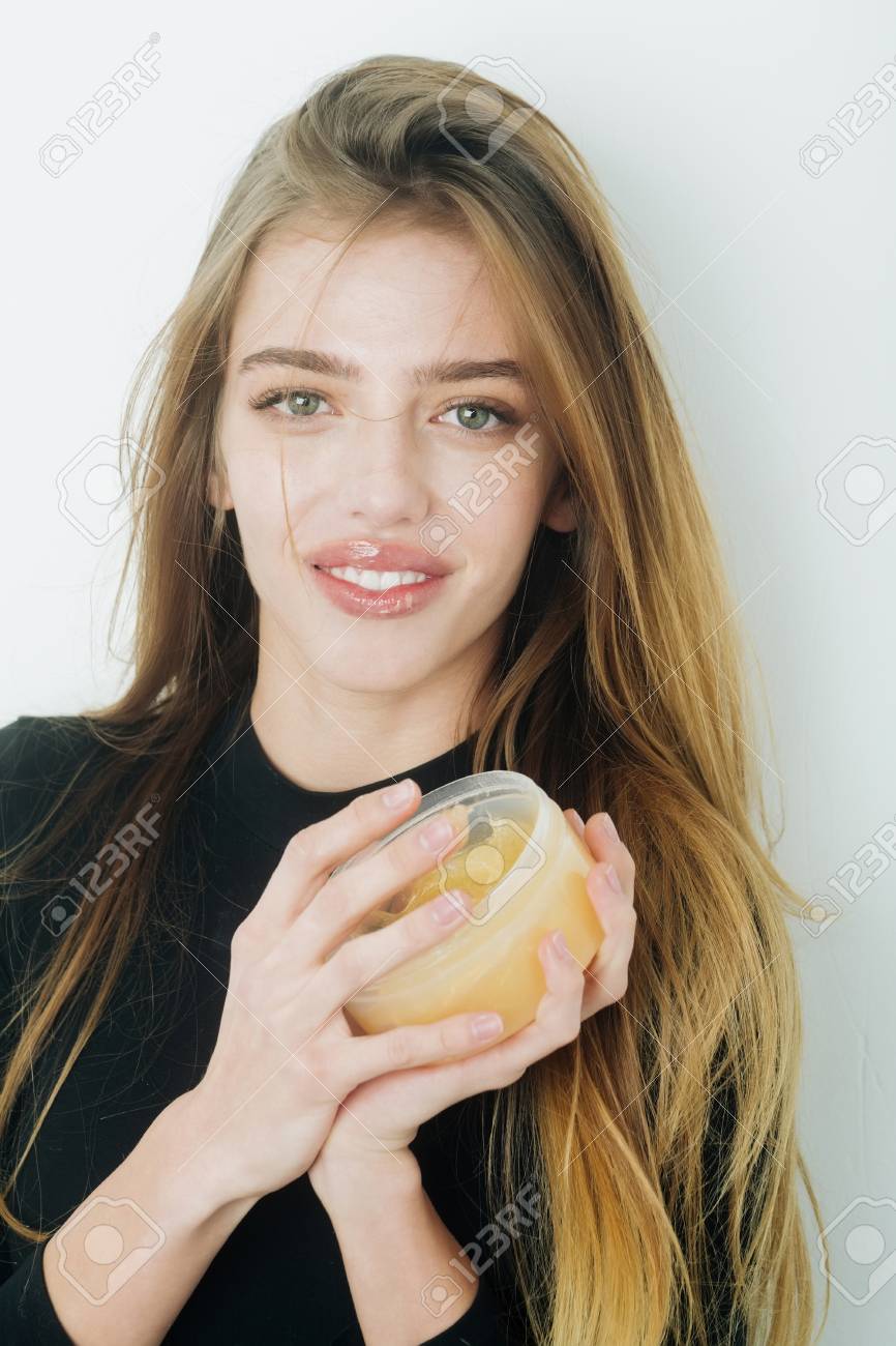 Glückliche hübsche Mädchen oder schöne Frau mit jungen Gesicht Haut und lange, blonden Haaren, ein Gel oder Balsam auf sexye Lippen aus Glas setzen Glückliche hübsche Mädchen oder schöne Frau mit jungen Gesicht Haut und lange, blonden Haaren, ein Gel oder Balsam auf sexye Lippen aus Glas setzen