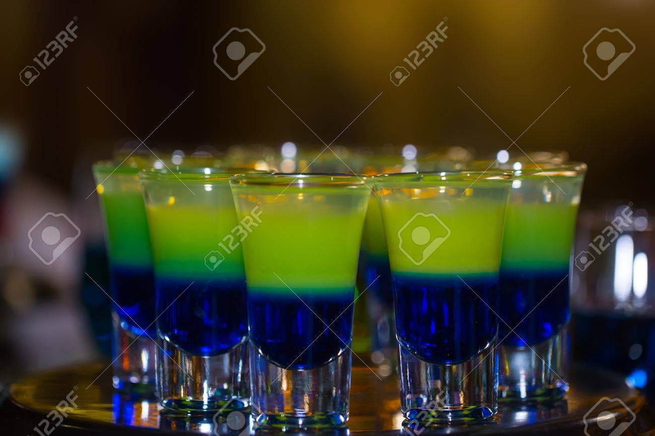 カクテル カウンターにて 青と黄色の階層型シューティング ゲームやアルコール飲料 混合のショット グラスでカクテルのバーやナイトクラブ背景をぼかした写真 の写真素材 画像素材 Image