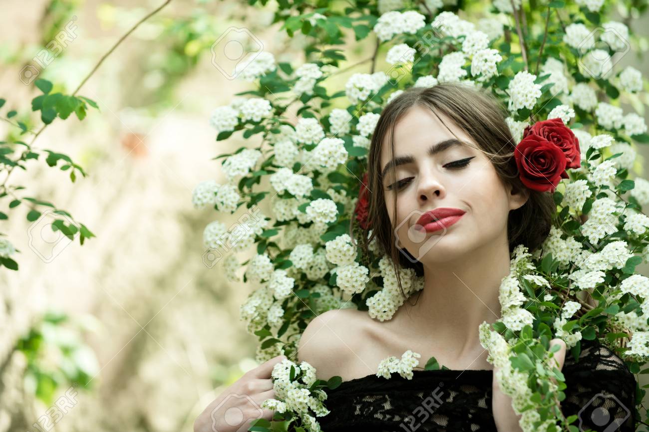 美容やファッション おしゃれな化粧と真っ赤な唇 きれいな女の子白い春または夏花自然な背景の上で黒のドレスで髪ヒスパニック系またはスペイン語スタイルでバラの花には の写真素材 画像素材 Image