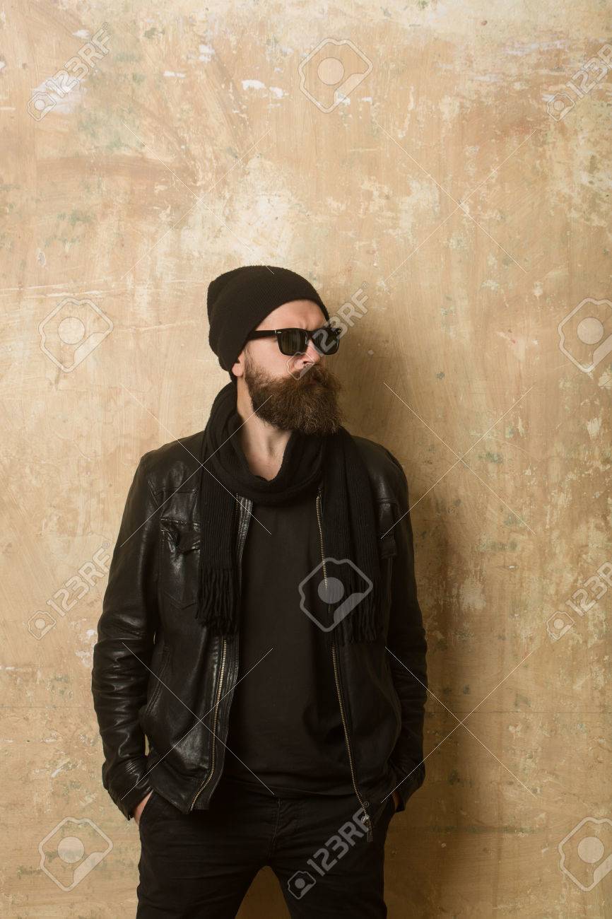 革のジャケットとメガネと帽子で流行に敏感 テクスチャ壁背景ファッション モデル 深刻な顔を持つ男 バイカー ファッションと美容 長いひげと口ひげを持つ男 の写真素材 画像素材 Image