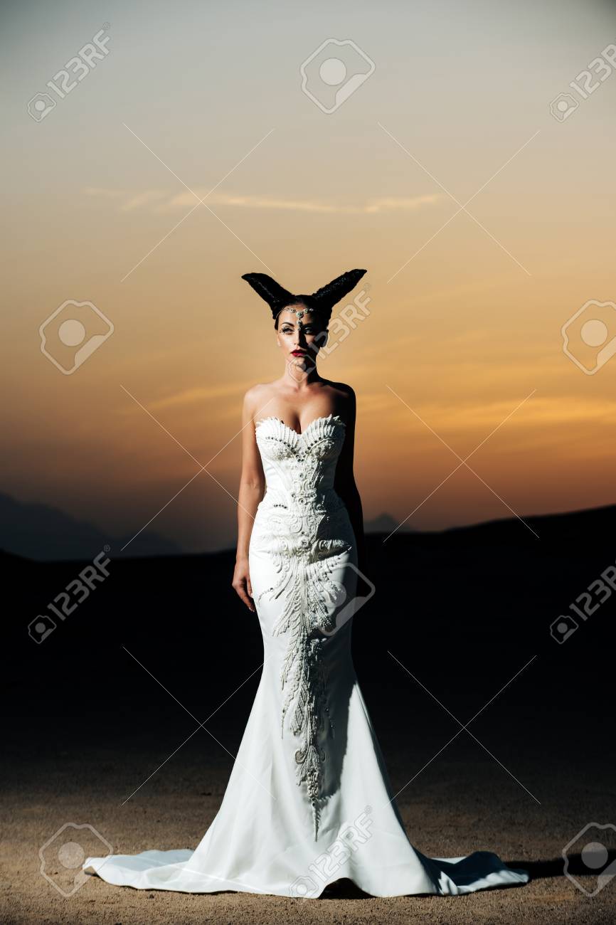 女性が夕焼け空にポーズします 砂漠で白の結婚式の女の子をドレスします 山の風景の砂丘の花嫁 ハネムーン旅行の概念 夏休みと休日 の写真素材 画像素材 Image