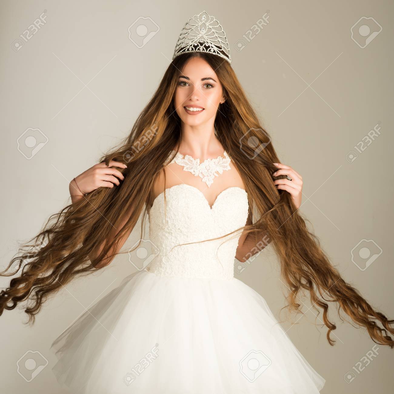 Beauty Salon And Wedding Fashion. Girl Has Fashionable Makeup And Healthy Hair On Grey Background. Haircare And Prom Queen. Hairdresser And Cosmetics. Woman With Long Hair White Dress And Crown. Stock Photo, Beauty Salon And Wedding Fashion. Girl Has Fashionable Makeup And Healthy Hair On Grey Background. Haircare And Prom Queen. Hairdresser And Cosmetics. Woman With Long Hair White Dress And Crown. Stock Photo,