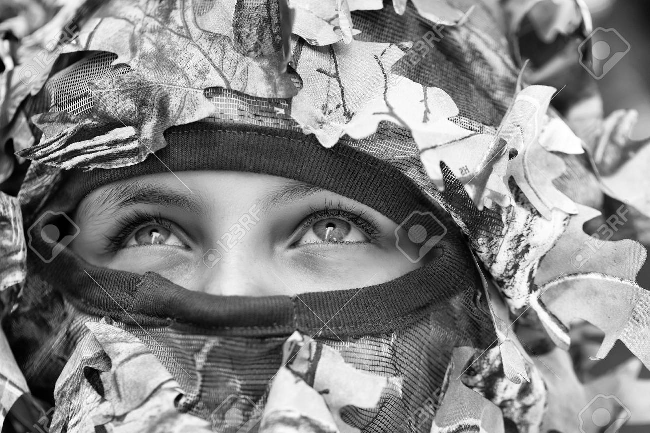 閉じた顔戦争迷彩とネットとマスクと軍のヘルメットで青い深刻な厳格な目を持つ小さな女の子 の写真素材 画像素材 Image