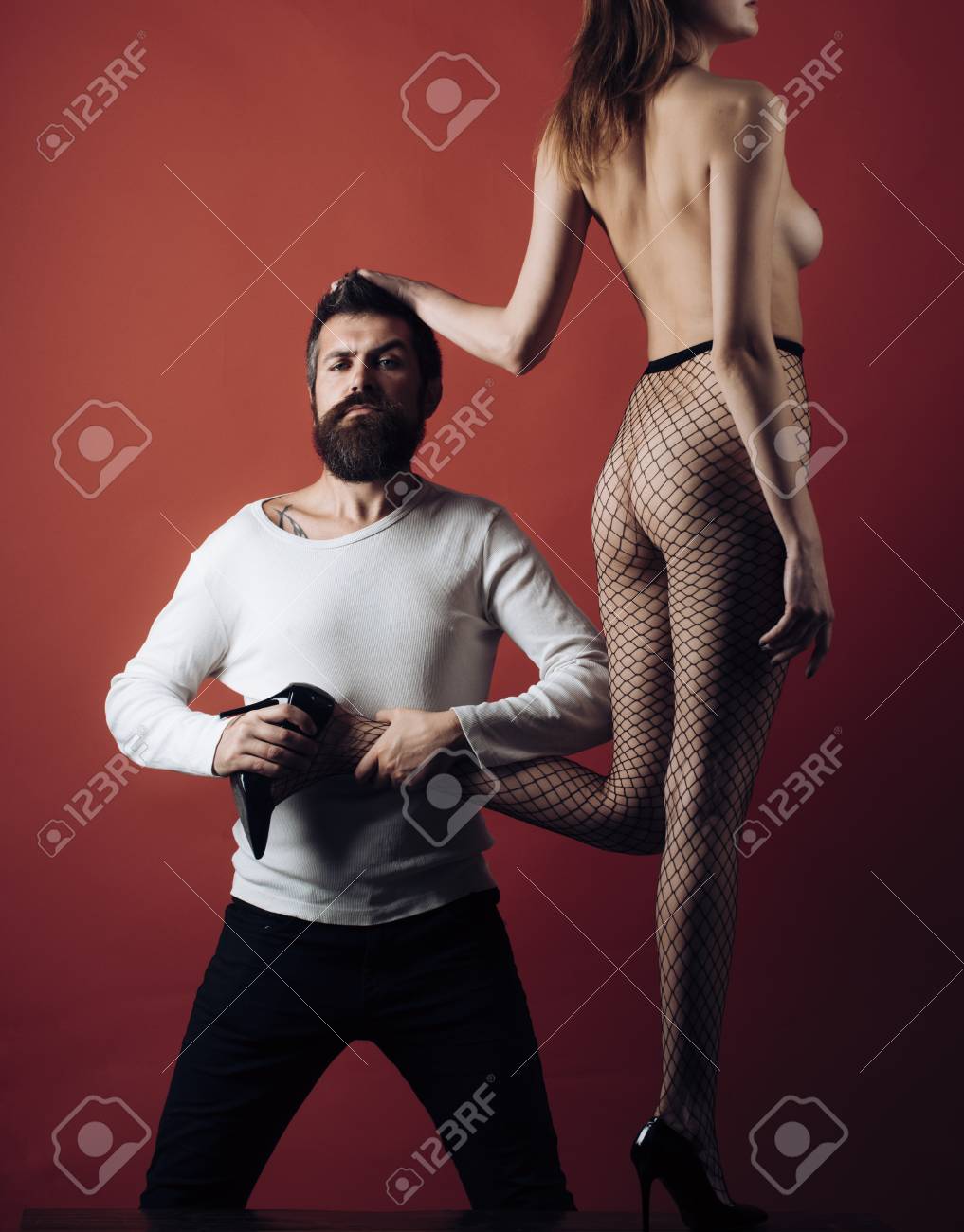 Mann Mit Strengem Gesicht Hält Weibliches Bein Und Setzt Stöckelschuh Auf  Ihren Fuß. Dame In Netzstrumpfhose Auf Burgunder Hintergrund. Hippie Fand  Sexy Nackte Aschenputtel, Kopienraum. Sexy Cinderella-Konzept. Lizenzfreie  Fotos, Bilder und Stock