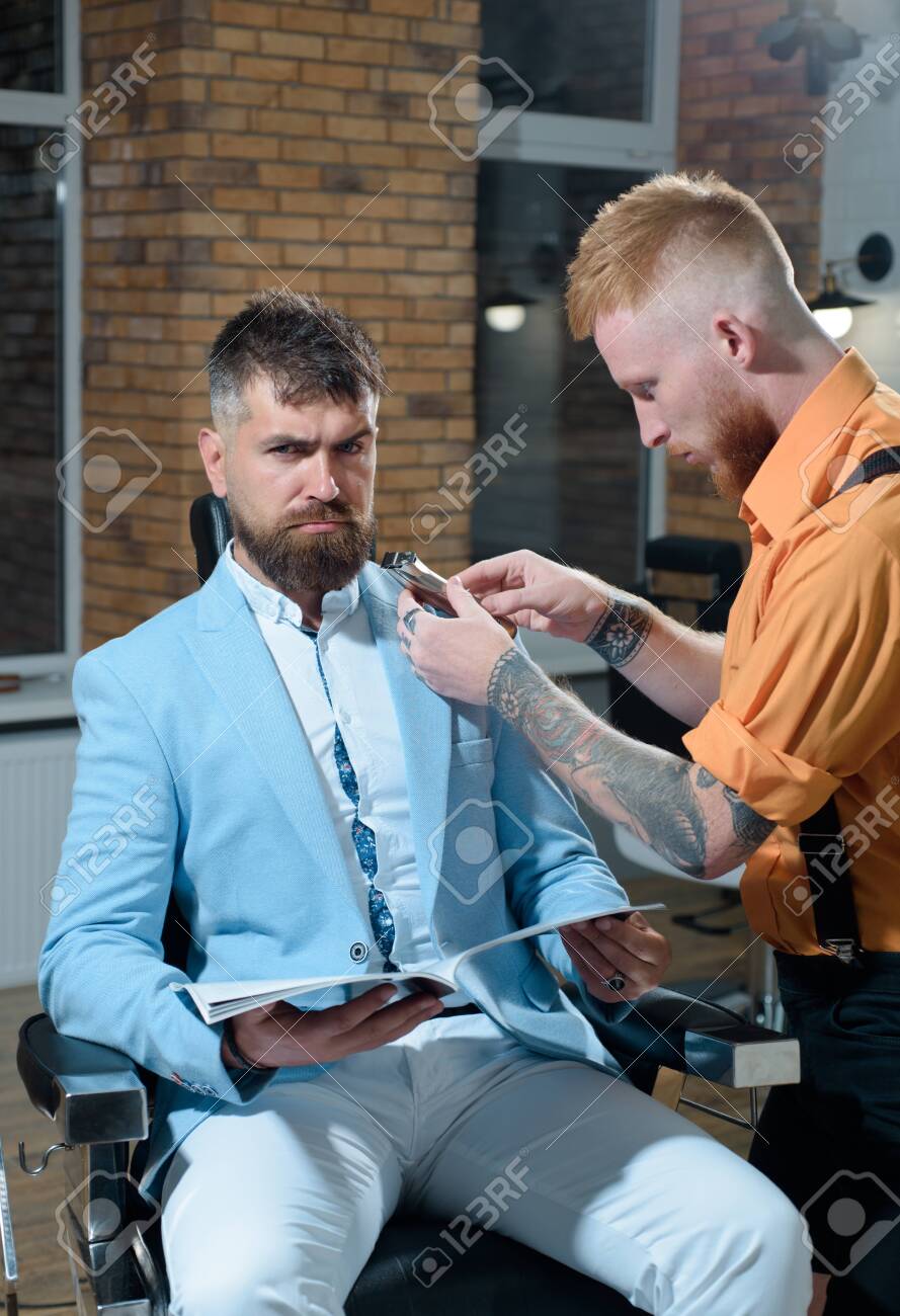 Barber Making Haircut Of Attractive Bearded Man In Barber Shop