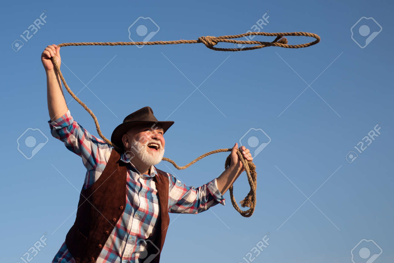 牧場やロデオで投げ縄ロープを持つ古いカウボーイ。茶色のジャケットと