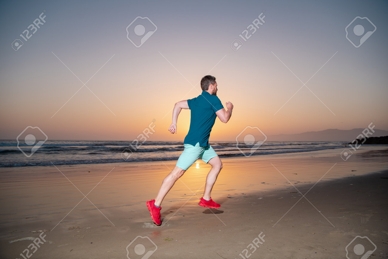 Man running on the beach at sunset. Man runner jogger running. - 168901892 Man running on the beach at sunset. Man runner jogger running. - 168901892