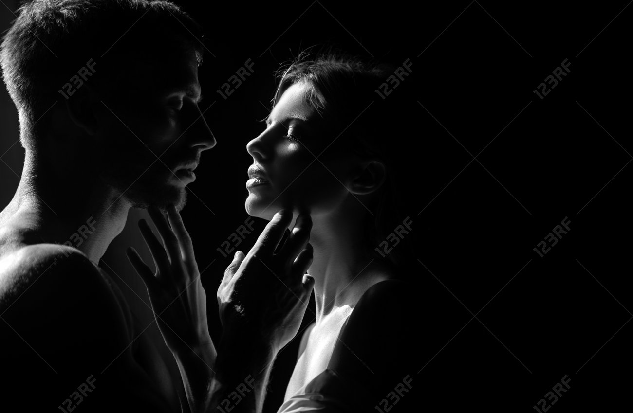 Silhouette of intimate embrace, man holding woman's face tenderly in dramatic black and white lighting