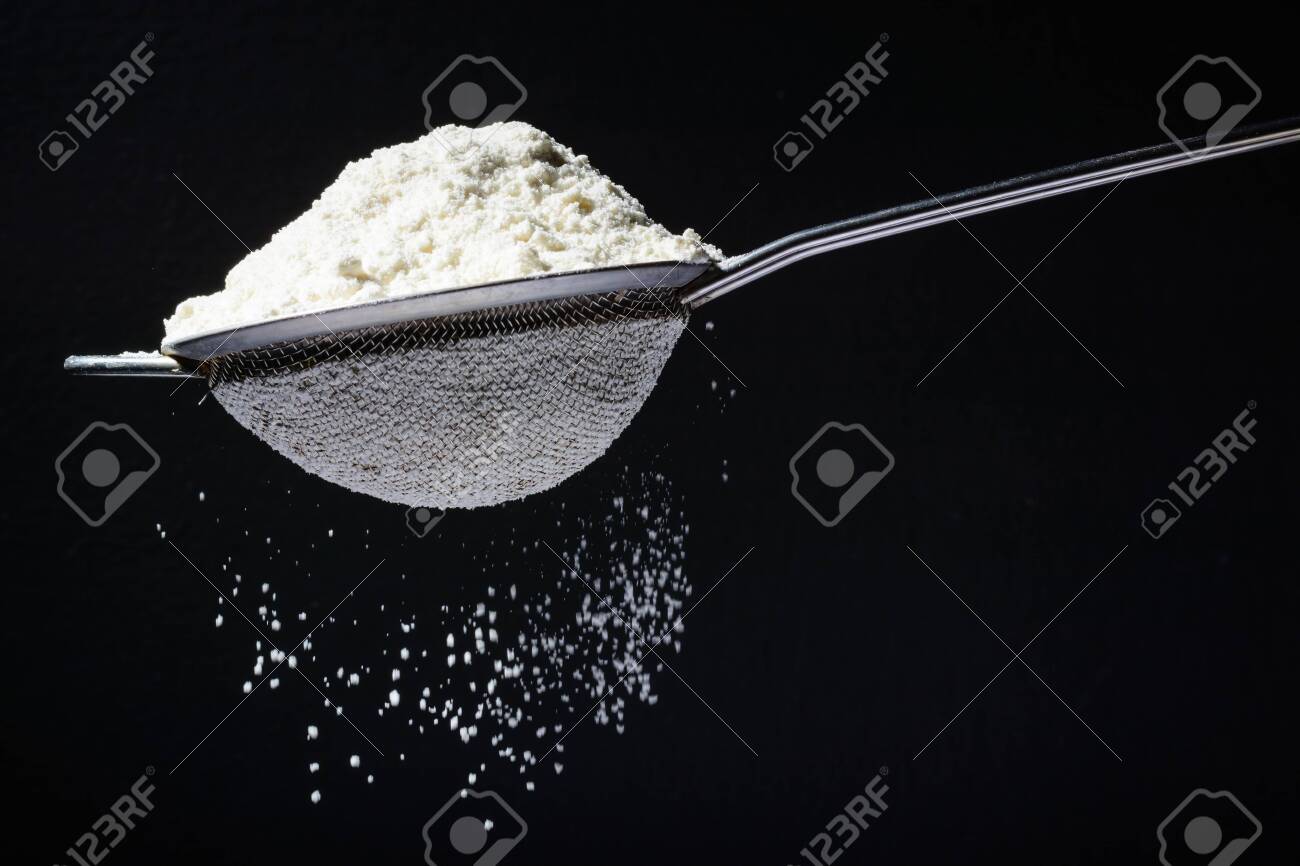 Flour is poured into a sieve, which sifts it. Dark and black background. Flour movement. - 121640275 Flour is poured into a sieve, which sifts it. Dark and black background. Flour movement. - 121640275