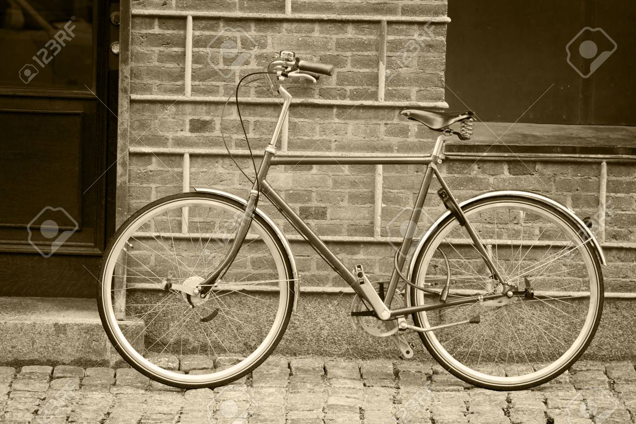 black and white image of an old style bicycle left on the street