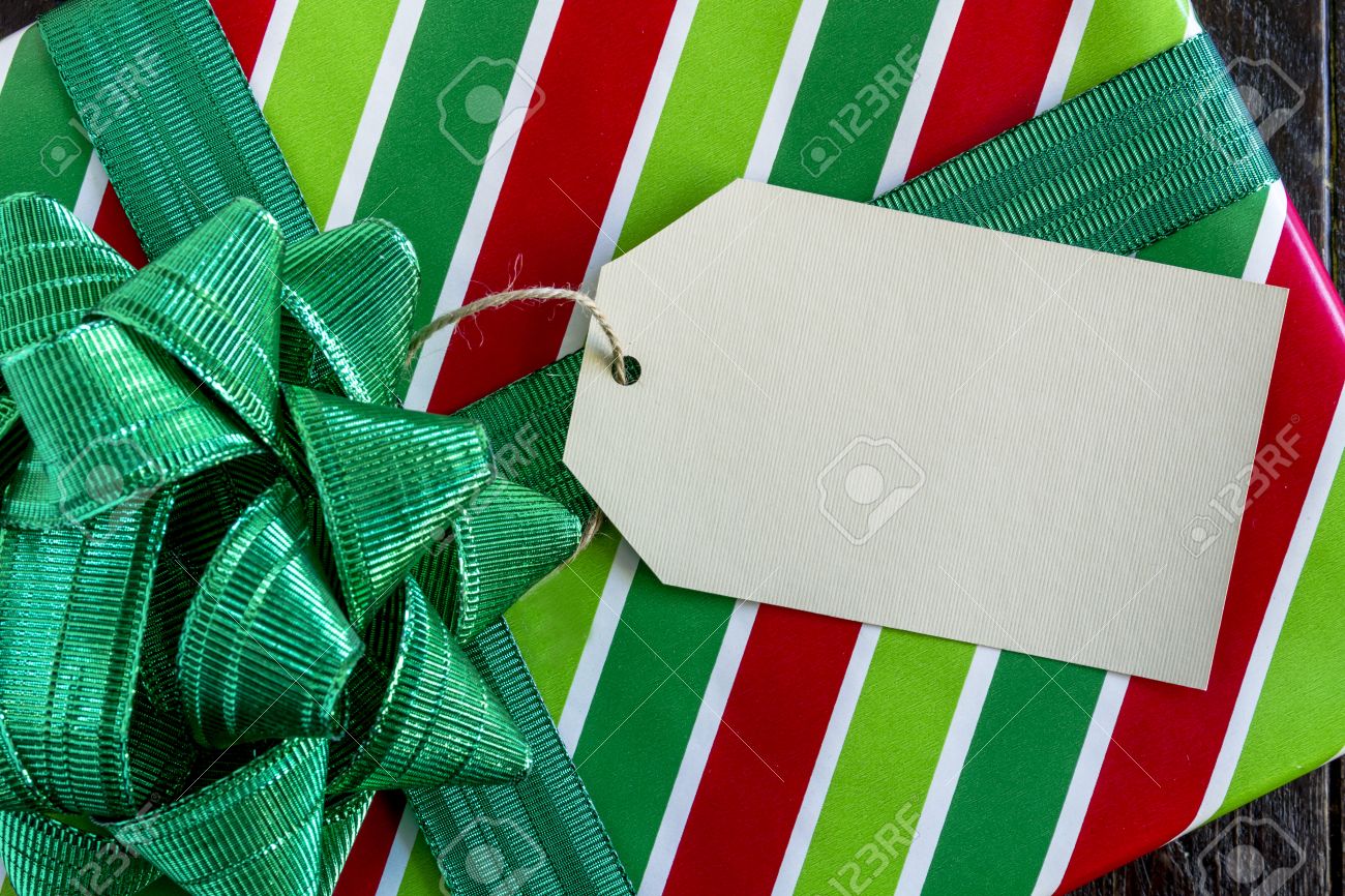 光沢のある緑色の弓と木製のテーブルの上に座って 空白のタグの赤と緑のストライプの包装紙に包まれたクリスマス プレゼント の写真素材 画像素材 Image