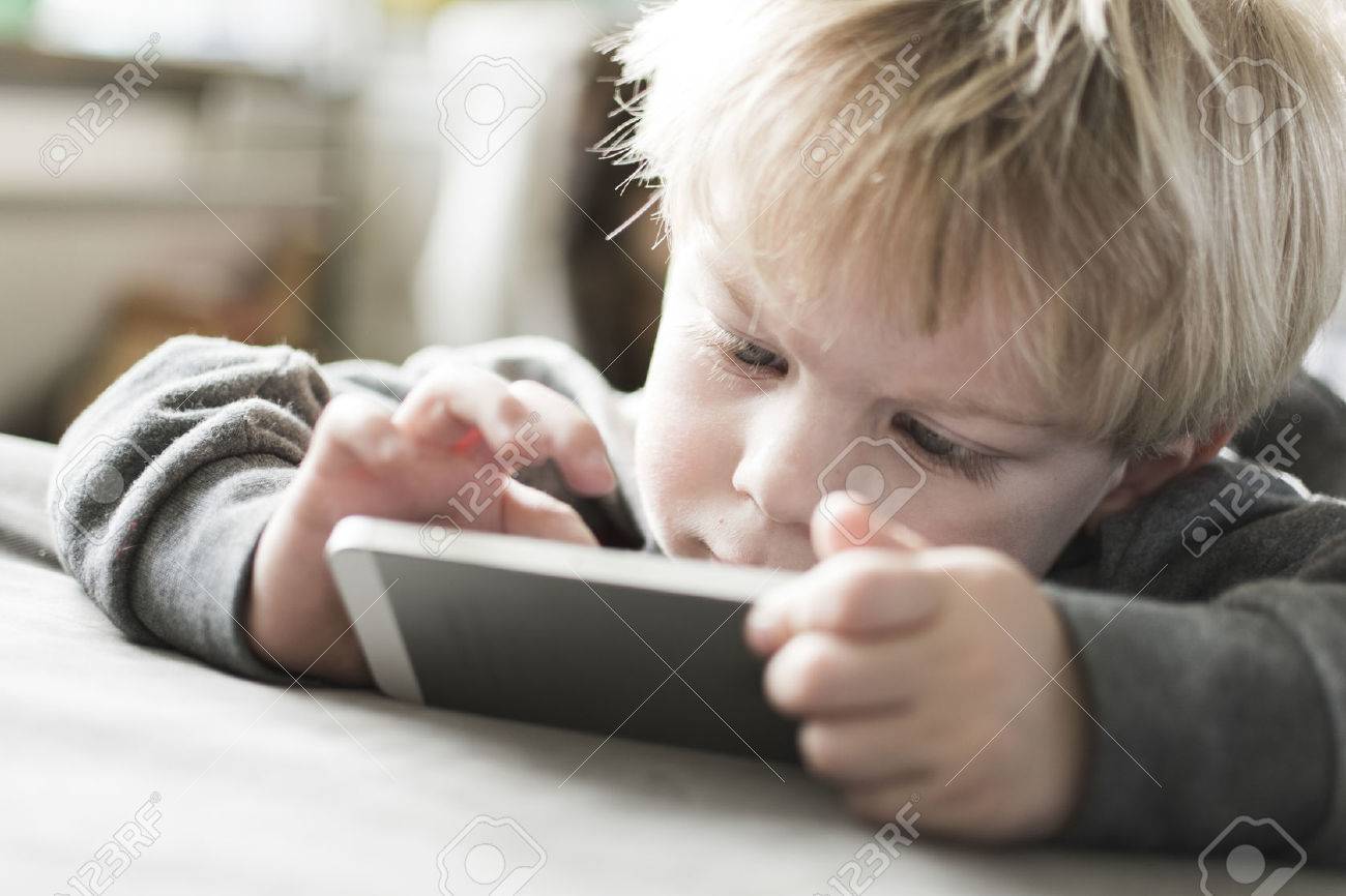 little kid playing game on smart phone - 26249508 little kid playing game on smart phone - 26249508