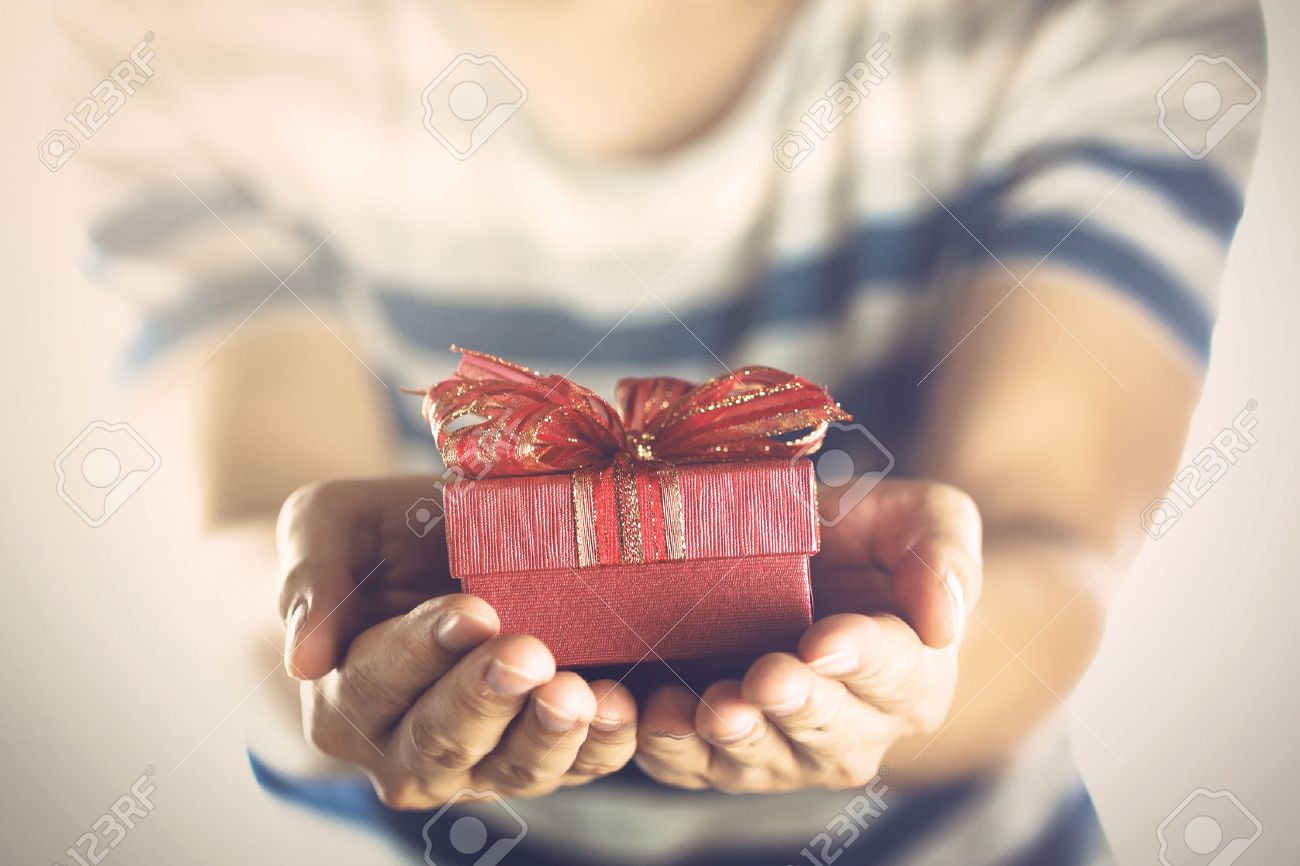 Young man giving and presenting a gift to someone. - 54759160 Young man giving and presenting a gift to someone. - 54759160