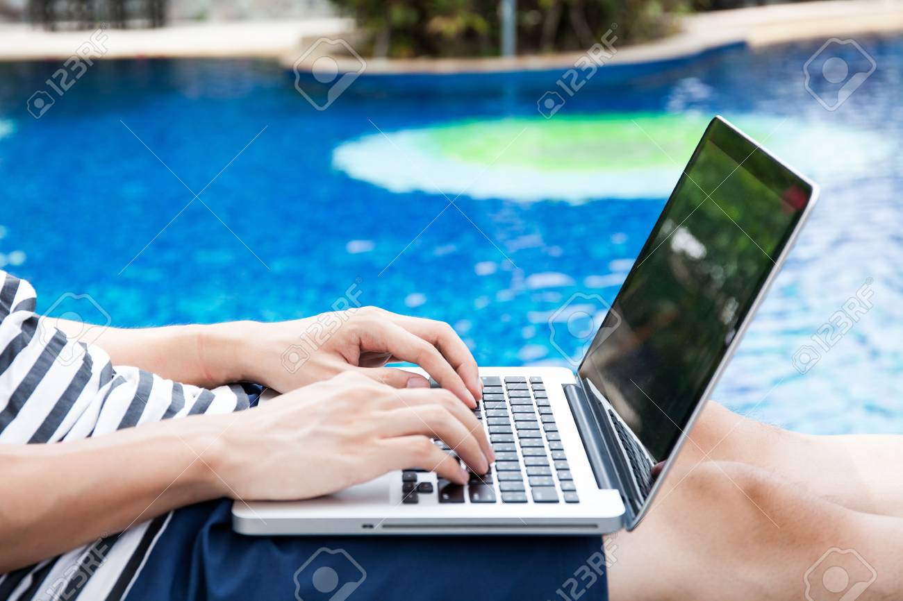 man using a laptop in the pool on vacation work anywhere and