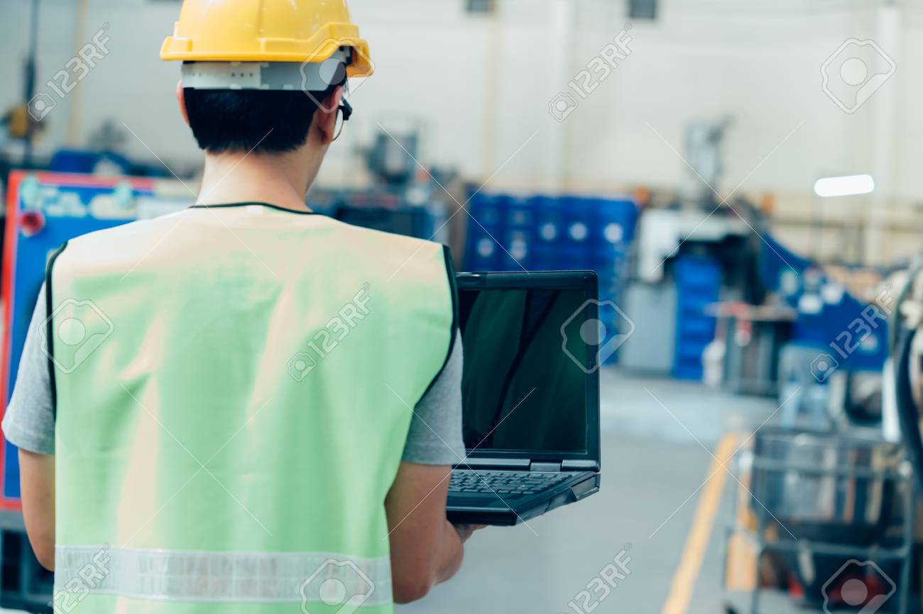 Asian male Industrial engineer in hardhat works with laptop in safety jacket at heavy industry factory. Processing plastic injection molding industry - 124609807 Asian male Industrial engineer in hardhat works with laptop in safety jacket at heavy industry factory. Processing plastic injection molding industry - 124609807