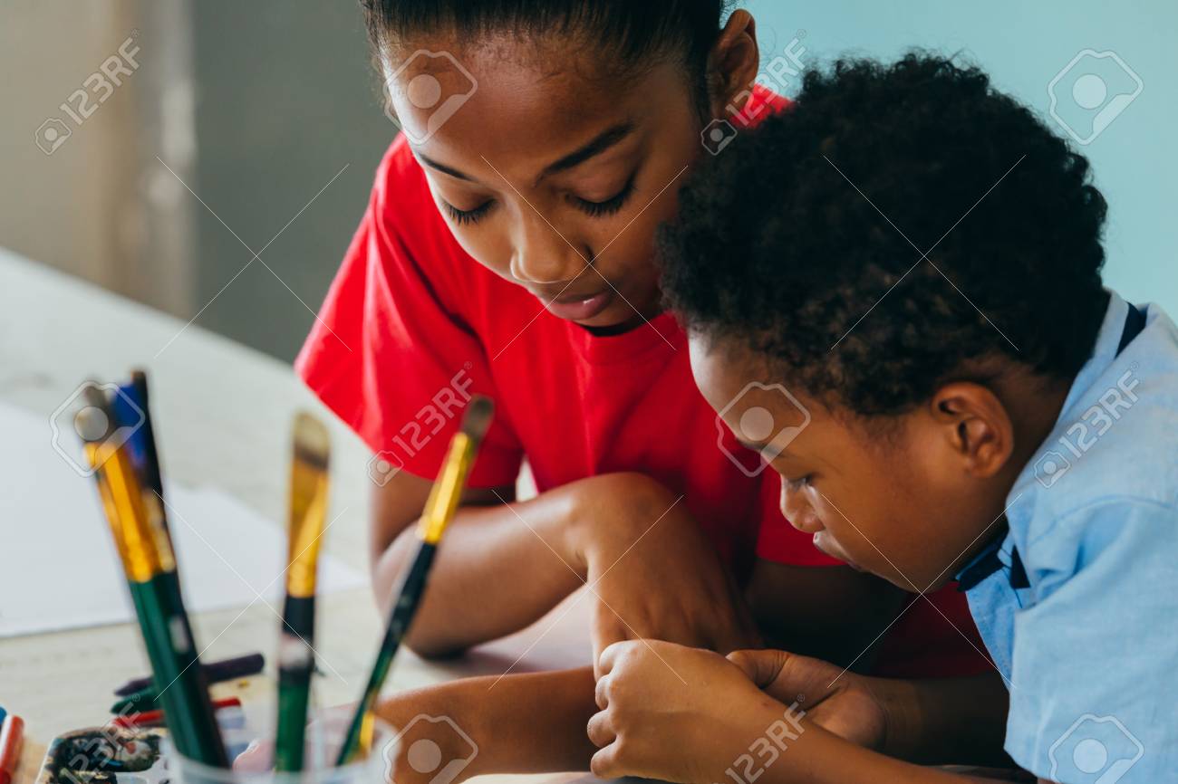 Closeup of elementary African American kids creatively drawing and painting with brushes and crayon - children creative education concept - 124612054 Closeup of elementary African American kids creatively drawing and painting with brushes and crayon - children creative education concept - 124612054
