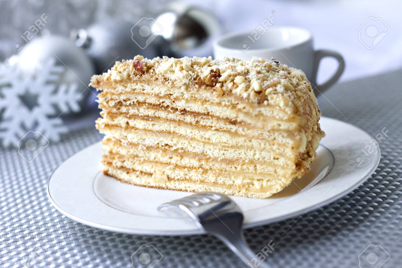 Morceau De Gâteau De Couche Avec Crème Et Noix Sur Une Plaque Avec Des Boules De Noël Sur Le Fond