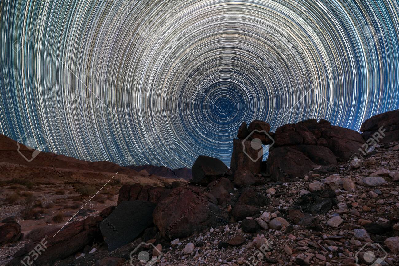 A beautiful night sky landscape with circular star trails, and interesting rock formations in the foreground and mountains on the horizon, in the Richtersveld National Park, South Africa. - 142556570 A beautiful night sky landscape with circular star trails, and interesting rock formations in the foreground and mountains on the horizon, in the Richtersveld National Park, South Africa. - 142556570